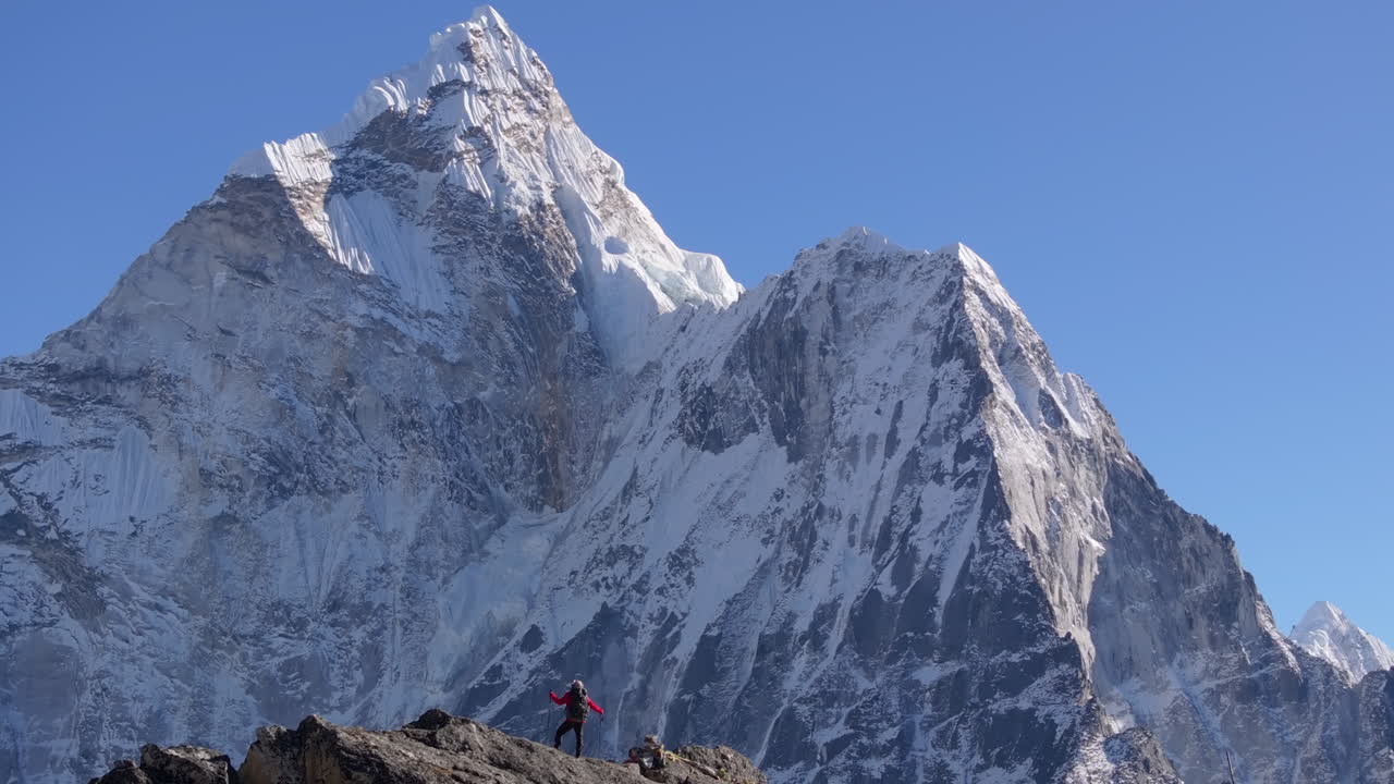 Un escursionista si erge sulla cima del Nangkartshang Peak vicino a Dingboche nella regione del Campo Base dell'Everest in Nepal, con il maestoso Ama Dablam e la catena himalayana a fare da sfondo