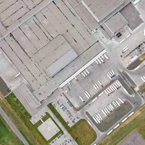 industrial area with trucks outdoors. aerial view of huge manufacturing complex in summer. camera moves around. slow motion.