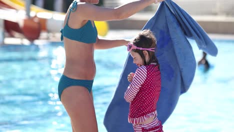 mother helps her child dry off after swimming at the pool