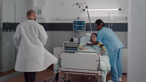 afro american nurse arrange sick woman bed during medical recovery