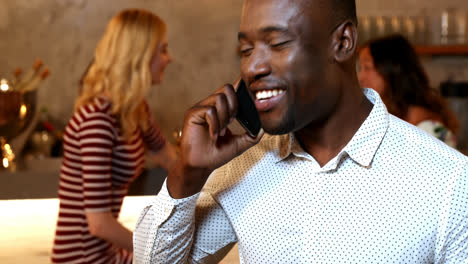 man talking on mobile phone while friends interacting in background 4k 4k