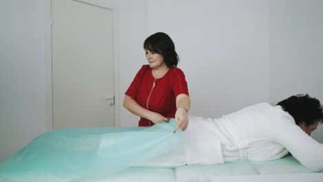 el terapeuta cubre las piernas del paciente de mediana edad con tela