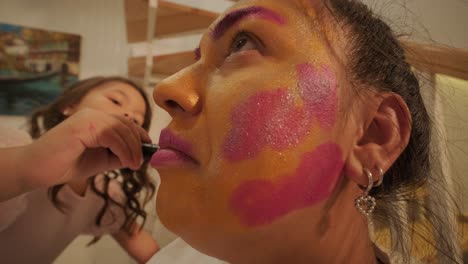 little girl applying makeup to her pregnant mother at home