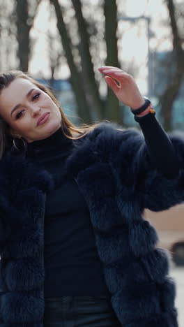 portrait of a sexy girl outdoors. attractive woman in a luxury fur coat in the park. beautiful young model on the city street background. slow motion. vertical video