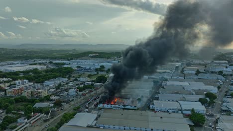 dark smoke rising from factory blaze with firefighters in rescue