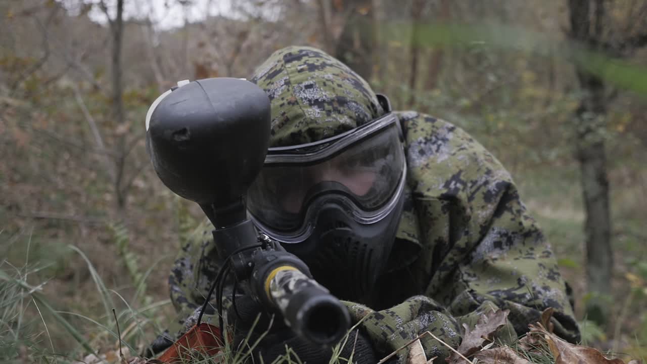 jugador de paintball en la hierba apuntando en cámara lenta