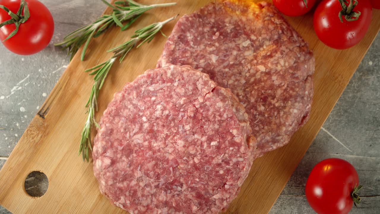 la carne cruda de la hamburguesa gira lentamente en una tabla de madera.