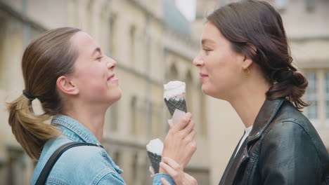 same sex female couple sightseeing and eating ice creams as they walk around oxford uk together