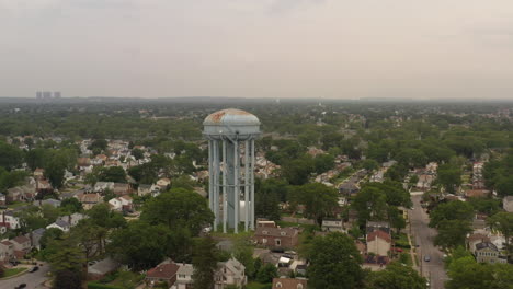 an aerial view over a suburban neighborhood with green trees on a cloudy day