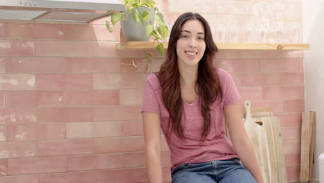 smiling woman relaxing in cozy kitchen with pink tile backsplash