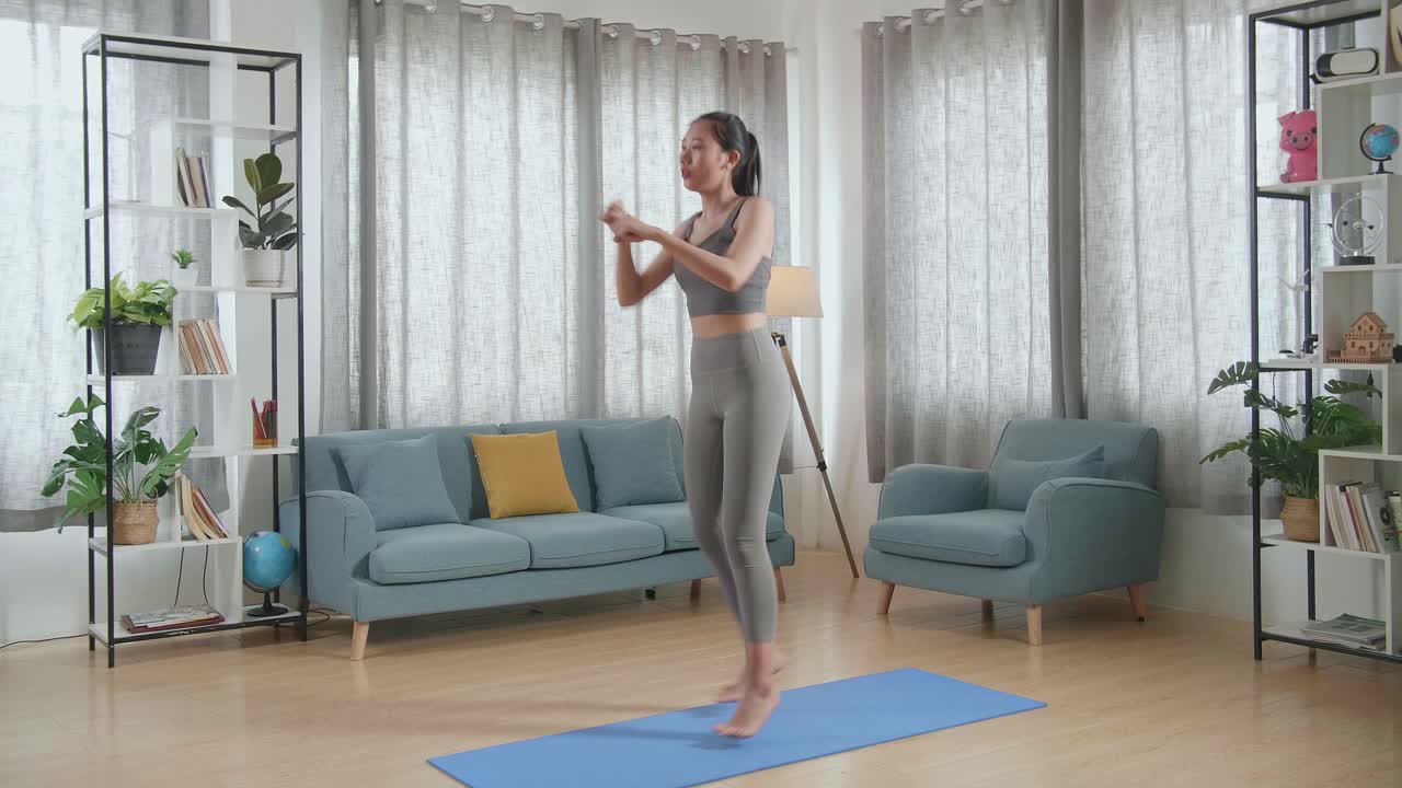 家でマットの上でカーディオコア強化運動をしているスポーツ服を着た若いアジア人アスリート女性