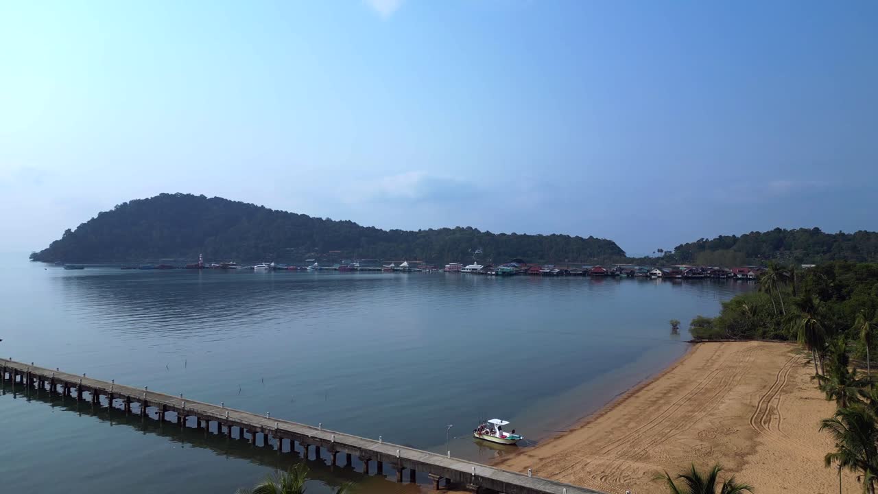 Bang Bao Pier floating village in Koh Chang island, Thailand, showing colorful houses and boats sailing in turquoise water. Lovely aerial view flight fly push forward drone
