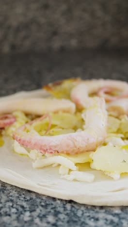 raw pizza with potatoes and octopus ready to go in the oven