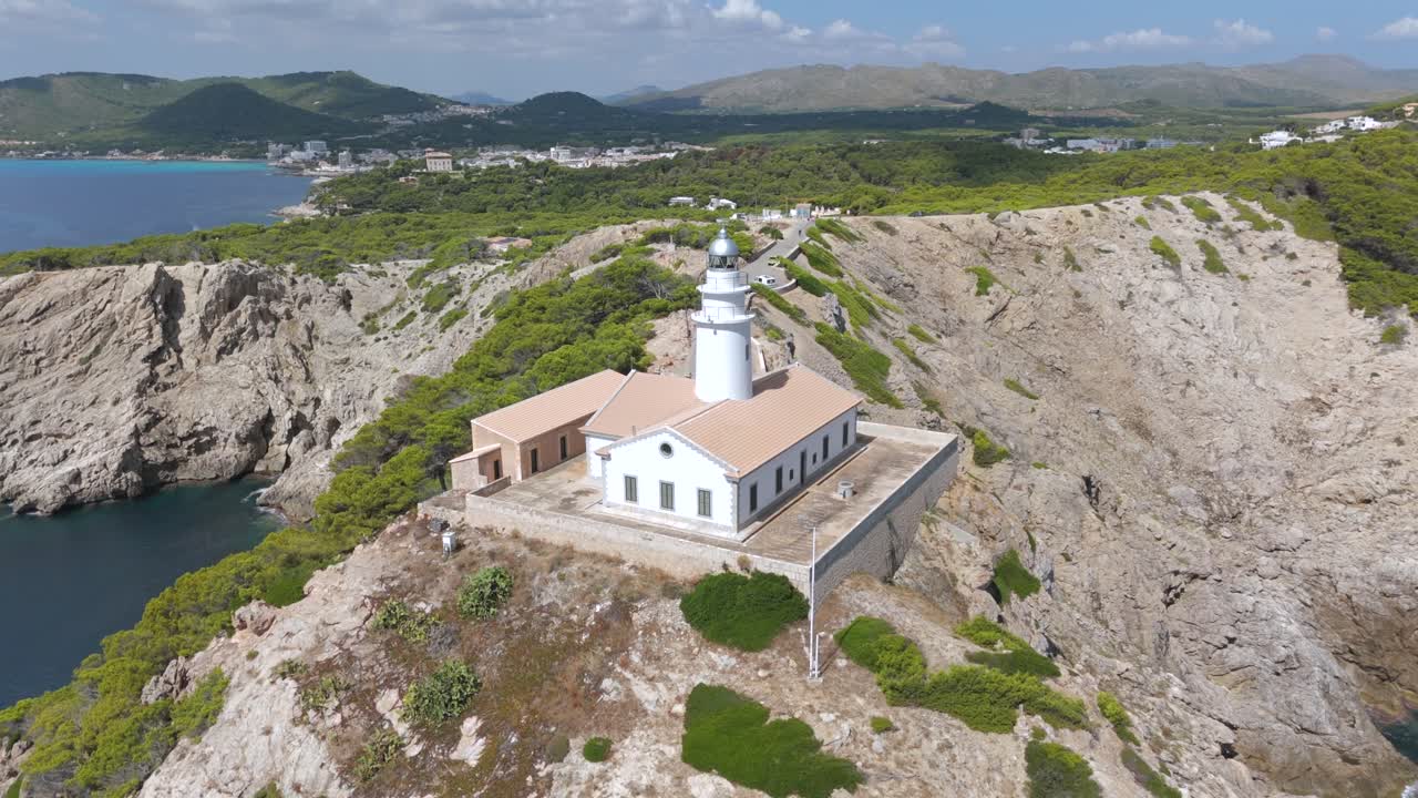 Drone orbiting Capdepera Lighthouse on rocky cliff overlooking the sea, Majorca