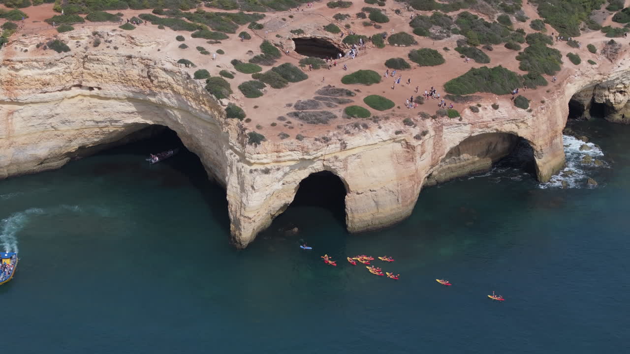 Aerial drone view of the Benagil Sea Cave and Atlantic Ocean coastline in Algarve, Portugal. Kayak tour sightseeing. Theme of overtourism and excessive tourism in Europe