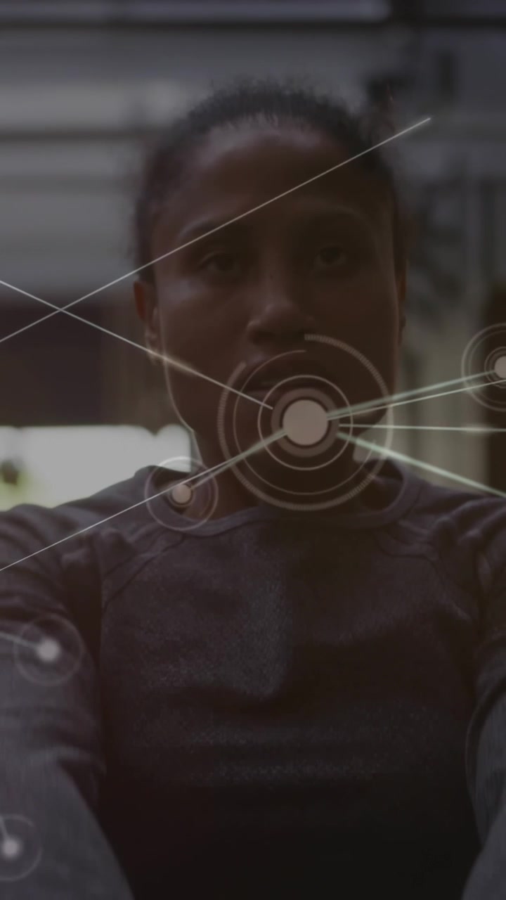 Vertical video: Woman raising hands in garage target popping over face forming node web for fitness