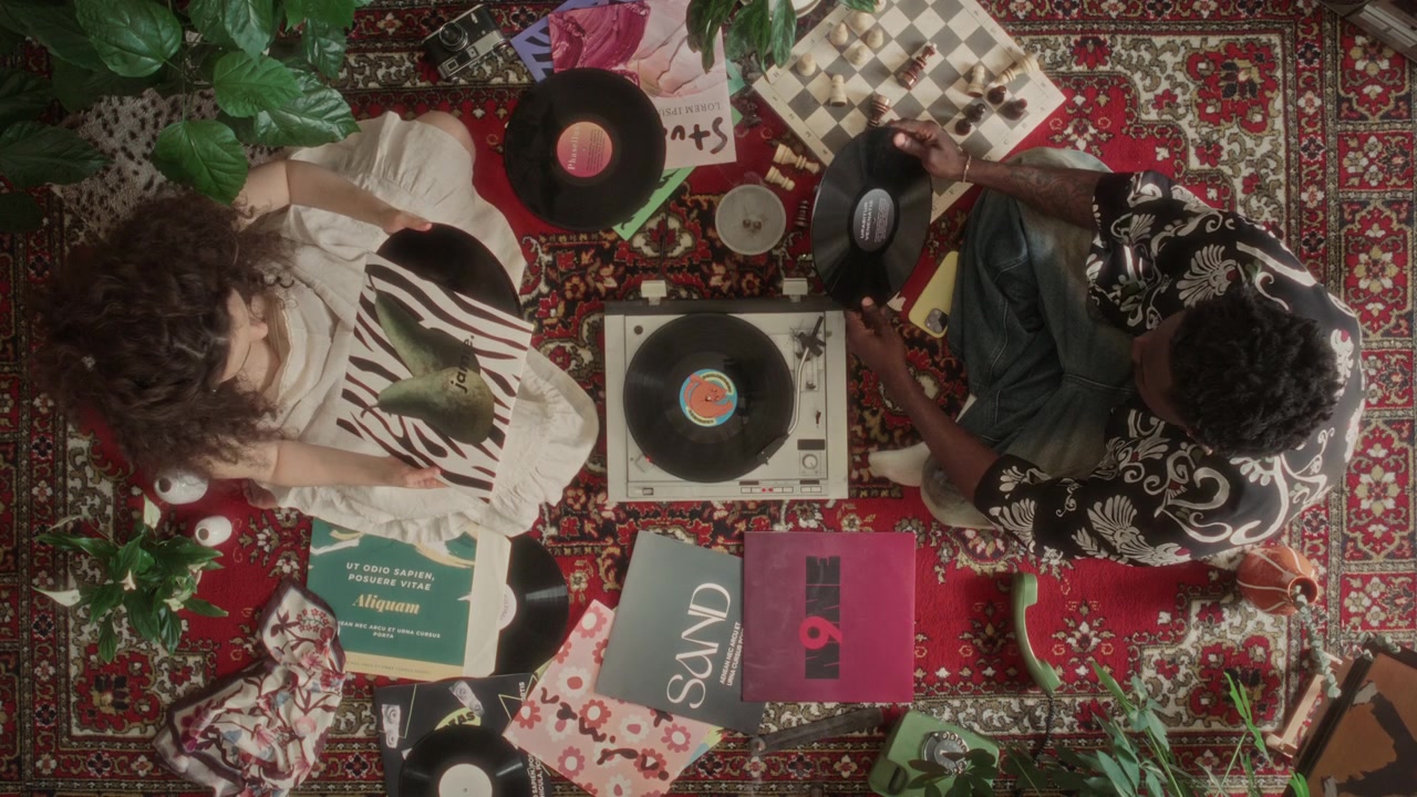 Vista dall'alto di giovane coppia che seleziona e riproduce dischi in vinile su giradischi retrò