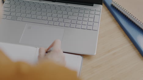 person working on laptop and notes