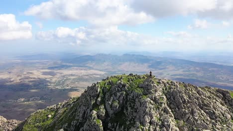 tiro de drone voando para cima e para frente a partir do penhasco da montanha e acima de uma pessoa parada na beirada olhando para a vista épica