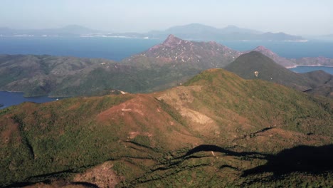 drone camera shot over the mountainous terrain full of lush green vegetation in hong kong geographical park in sai kung in the evening