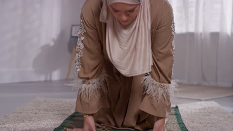 muslim woman wearing hijab at home praying kneeling on prayer mat 8