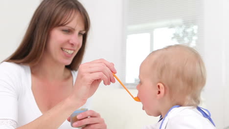 Woman feeding a baby with orange spoon