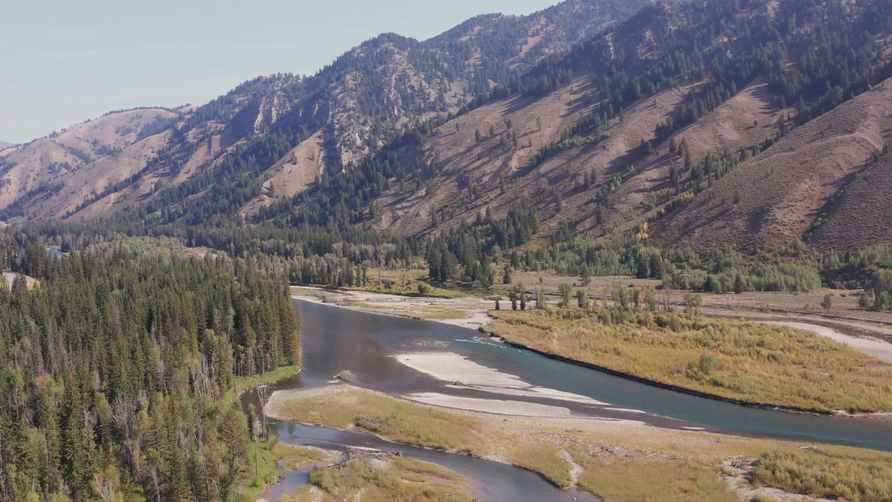 Luftdroneoptagelse af Snake River, der passerer over sandbanker og klippefyldte flodbredder. Fremadgående sporing og nedadgående tilt. Optaget i 4K.