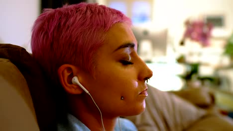 mujer escuchando música en los auriculares en la sala de estar 4k