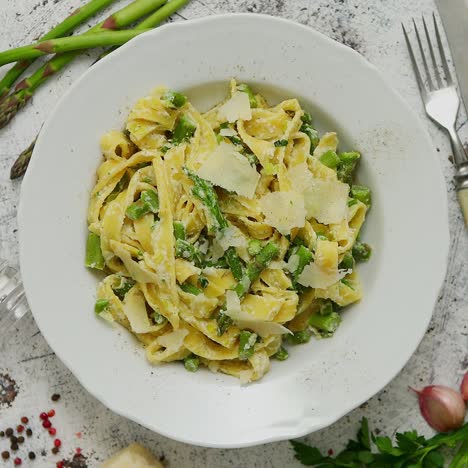 Tagliatelle-pasta-with-creamy-ricotta-cheese-sauce-and-asparagus-served-white-ceramic-plate