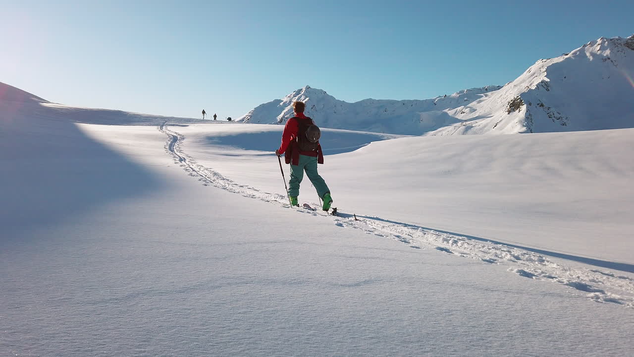Orbiting a young cross country skier as they ascend steep snow covered slope in the Austrian Alps, slow motion