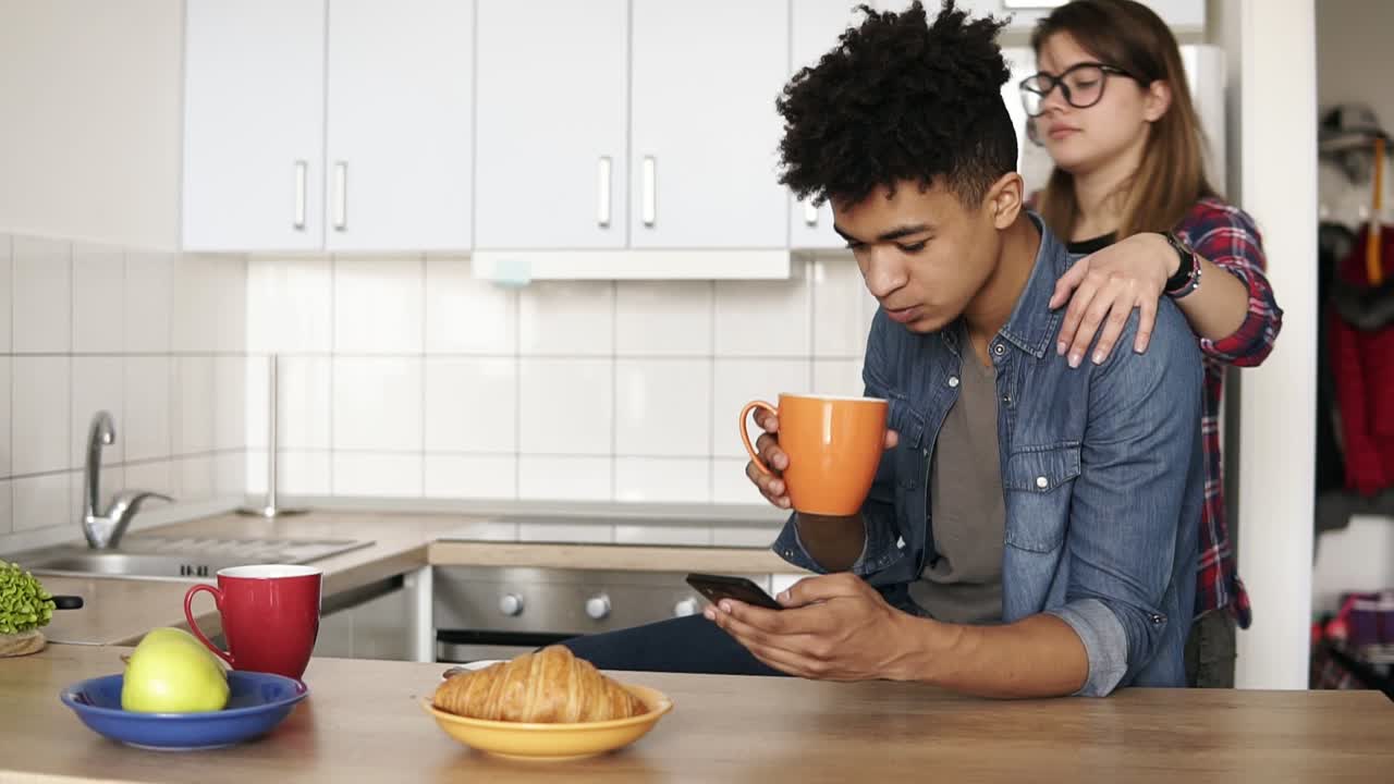 imágenes en cámara lenta de una chica caucásica besando a su novio mulato en la mejilla y adorables abrazos después en su cocina