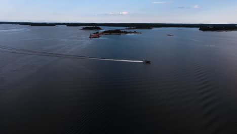 Vista-Aérea-De-Una-Lancha-Rápida-Conduciendo-En-El-Archipiélago-De-Aland,-Tarde-De-Verano-En-Finlandia---Pan,-Tiro-De-Drone