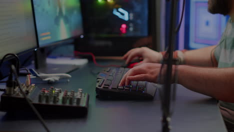 primer plano de streamer escribiendo en el teclado rgb jugando un videojuego de disparos espaciales