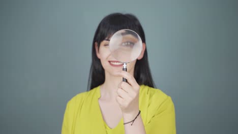 woman looking at camera with magnifying glass.