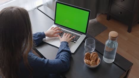 High-angle-view-of-woman-typing-on-laptop-green-screen-keyboard-in-office