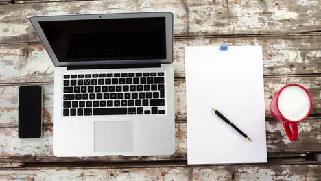 coffee cup, laptop, mobile phone, clipboard, pen on wooden plank