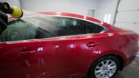 car washing cleaning with foam and high pressured water. red car