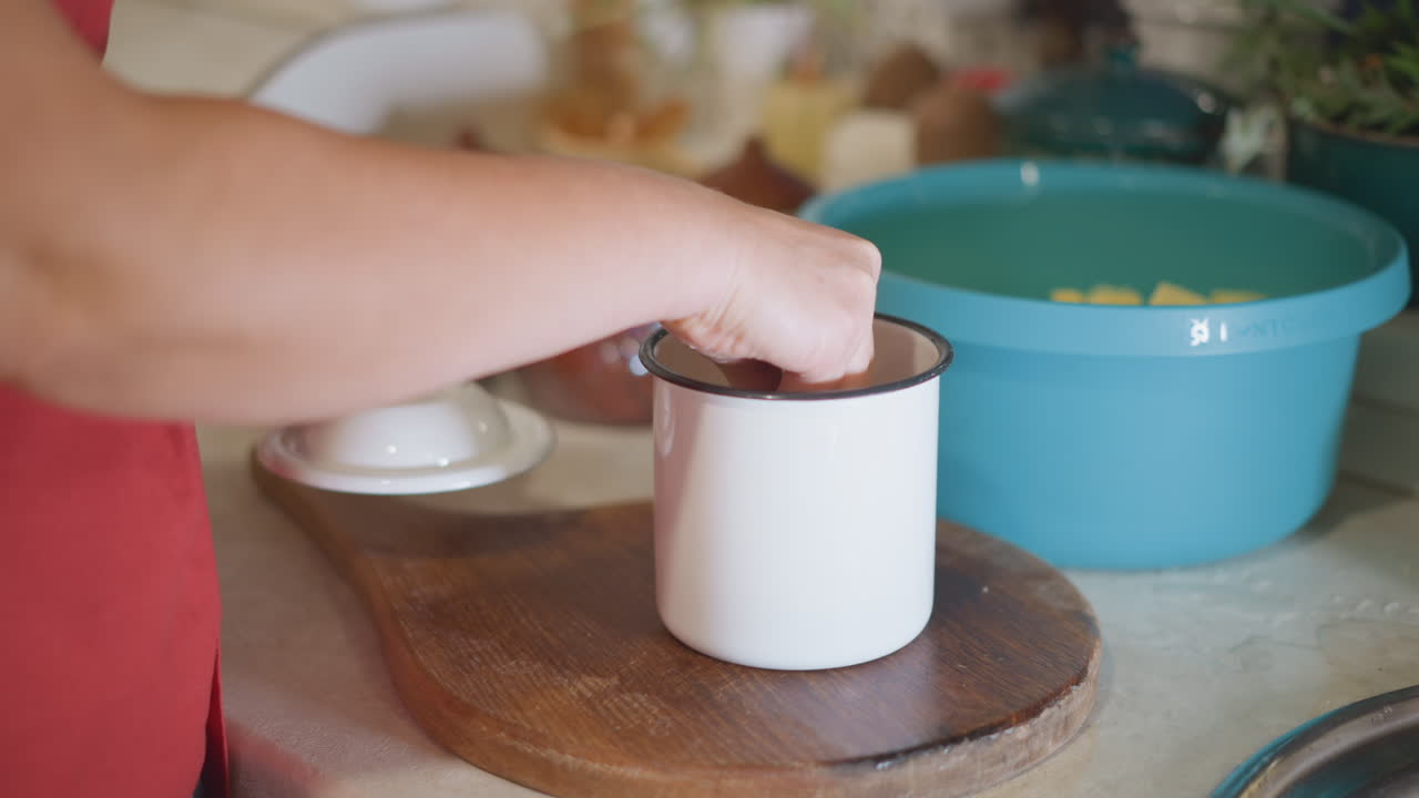 Cook covering pot. Home chef carefully places lid on pot. Person in kitchen gently puts lid on enamel cookware. Traditional home cook carefully covering saucepan in cozy kitchen environment