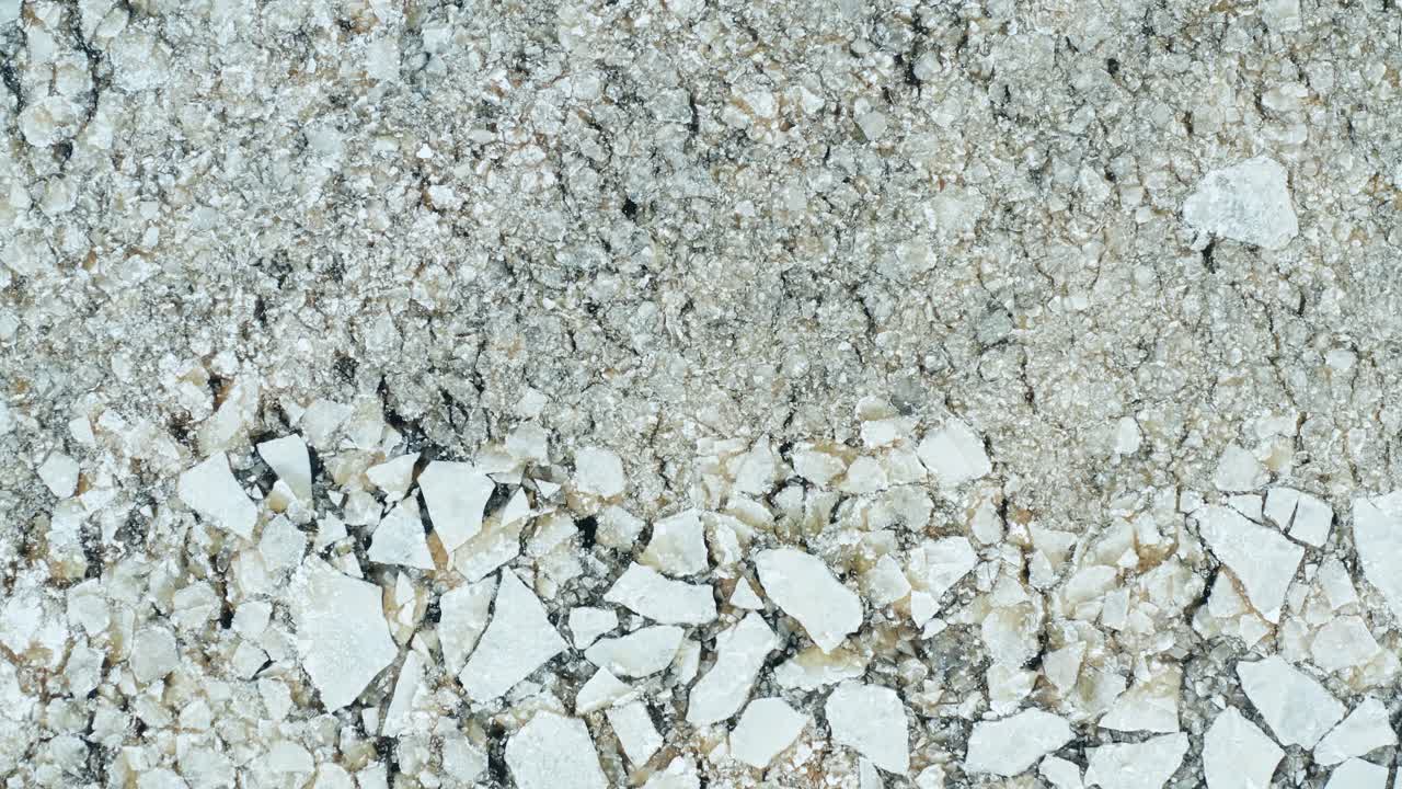 Veduta aerea in sorvolo di lastroni di ghiaccio incrinati che galleggiano nel mare