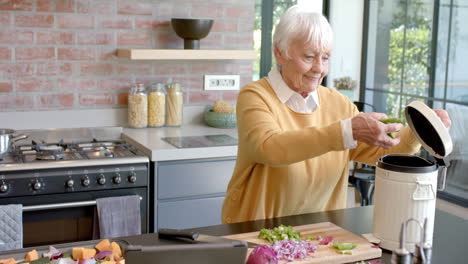 Mujer-Caucásica-Mayor-Limpiando-Cáscaras-De-Verduras-En-La-Cocina-De-Casa,-Cámara-Lenta,-Espacio-Para-Copiar