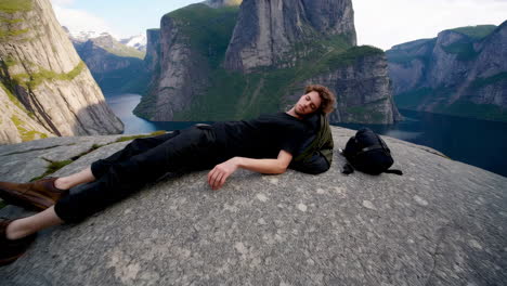 a man relaxing on a rocky outcrop overlooking a stunning norwegian fjord