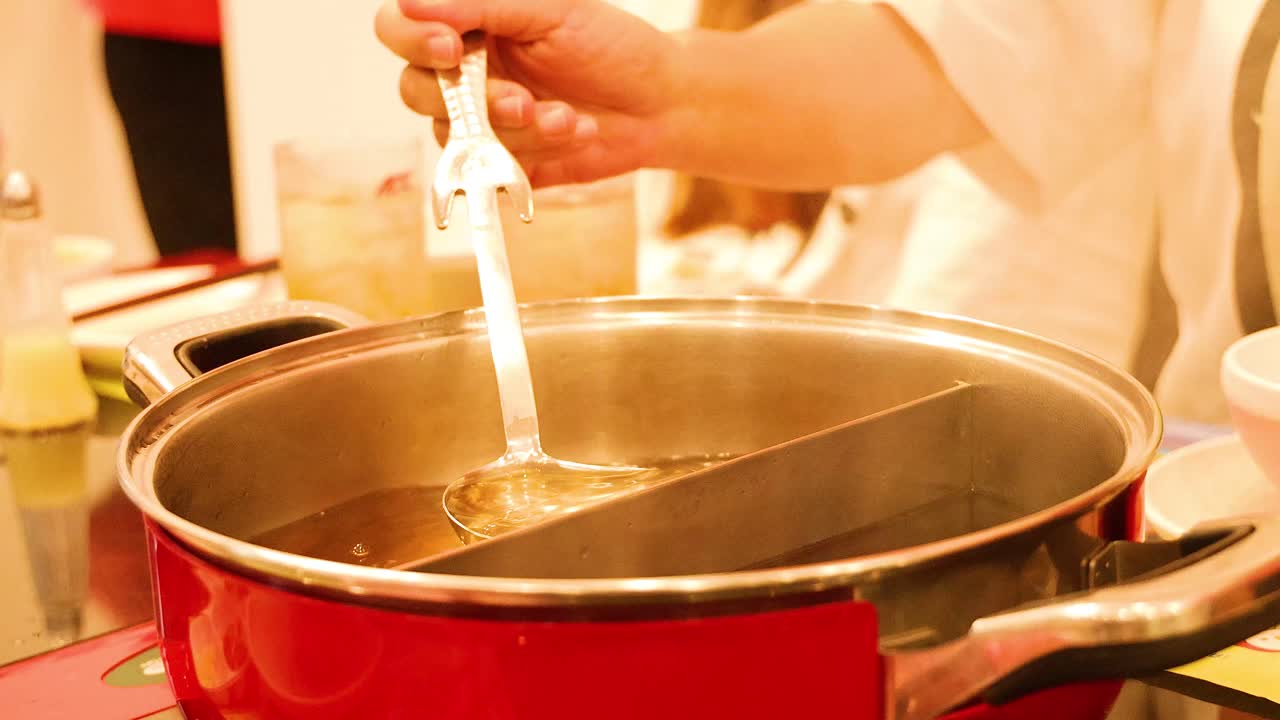 Chef preparing sukiyaki with ladle in hot pot