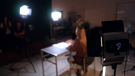 soffits illuminate a woman sitting in studio at desk. behind the stages in the modern photo studio during footage.