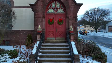 slow push in on church door decorated with christmas wreaths