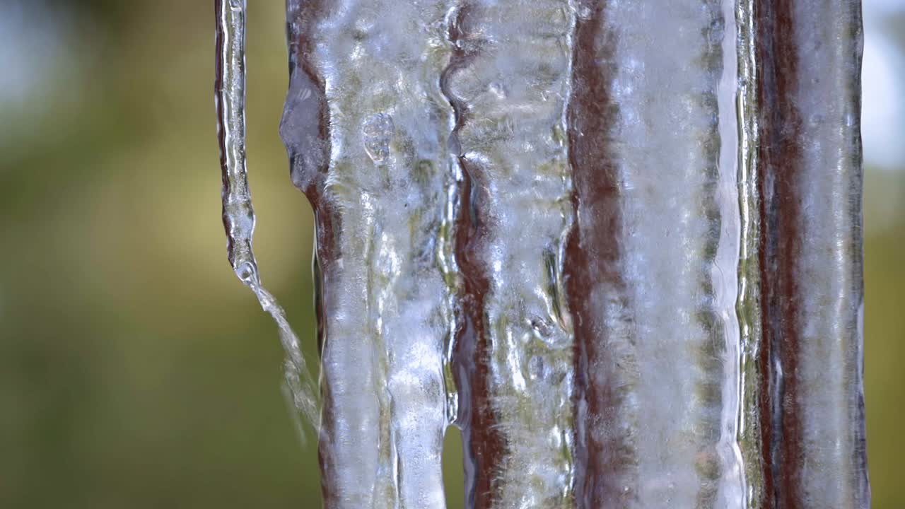Extreme close up of a group of hanging icicles on the deck of a home with water melting and running down the ice and dripping of the points