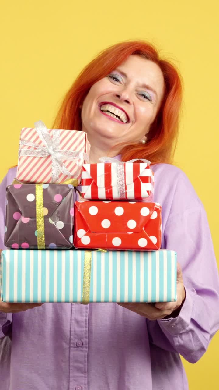 A woman joyfully holding a stack of colorful wrapped gifts