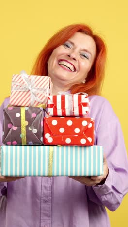 a woman joyfully holding a stack of colorful wrapped gifts