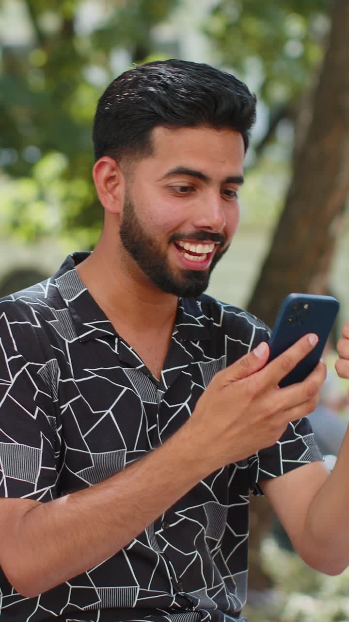 Indian man using mobile smartphone celebrating win good message online ...