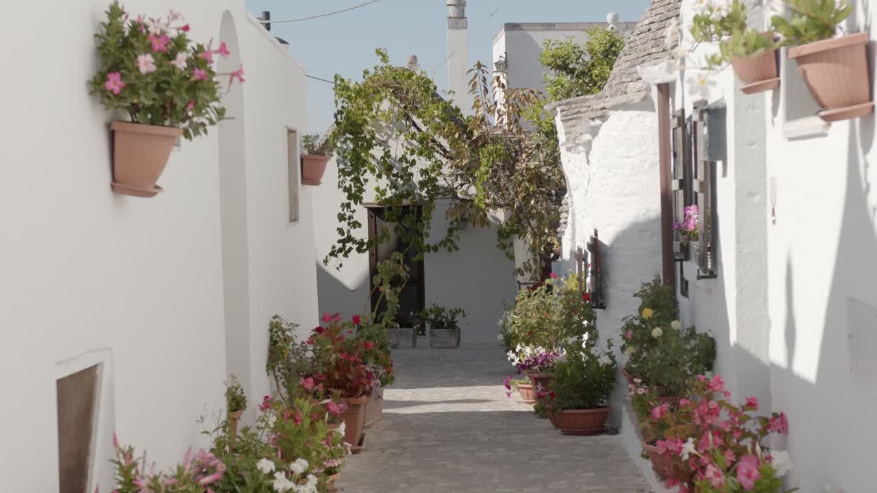 callejón de la casa blanca con flores de colores en alberobello