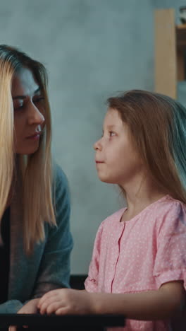 happy blonde mother gives prescribed drug to cute little daughter to cure infectious disease at small table in semi-dark room at home close view slow motion